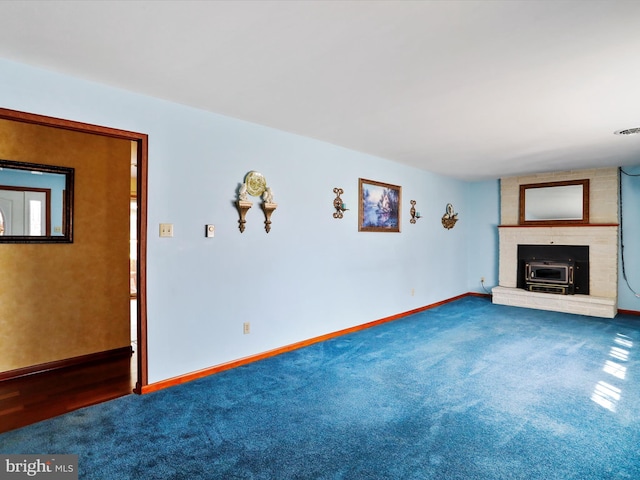 unfurnished living room featuring carpet and a wood stove