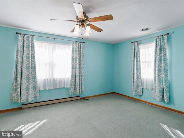 carpeted empty room featuring baseboard heating, ceiling fan, and plenty of natural light