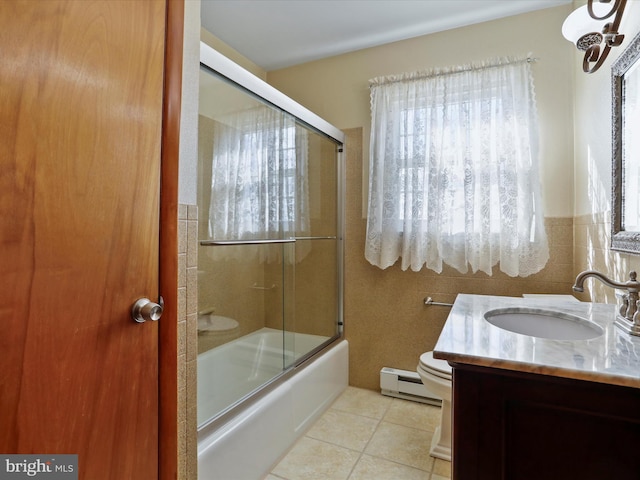 full bathroom with a baseboard radiator, bath / shower combo with glass door, toilet, vanity, and tile patterned flooring