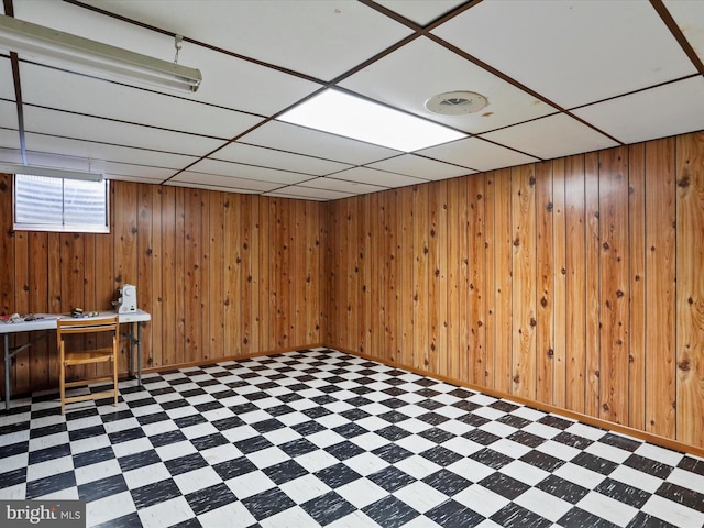 basement with wooden walls, a paneled ceiling, and indoor bar