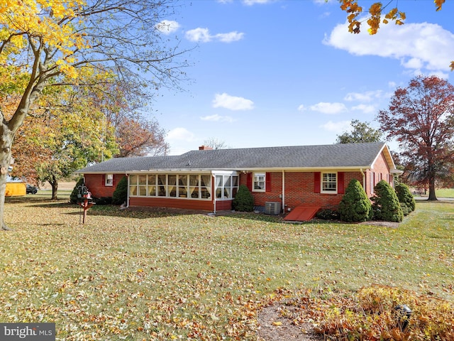 single story home with a sunroom, a front lawn, and central AC unit