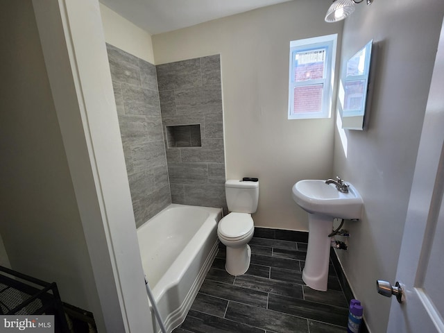 bathroom with toilet and tiled shower / bath