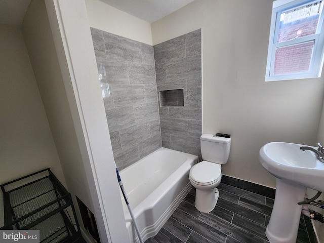 bathroom with toilet and tiled shower / bath