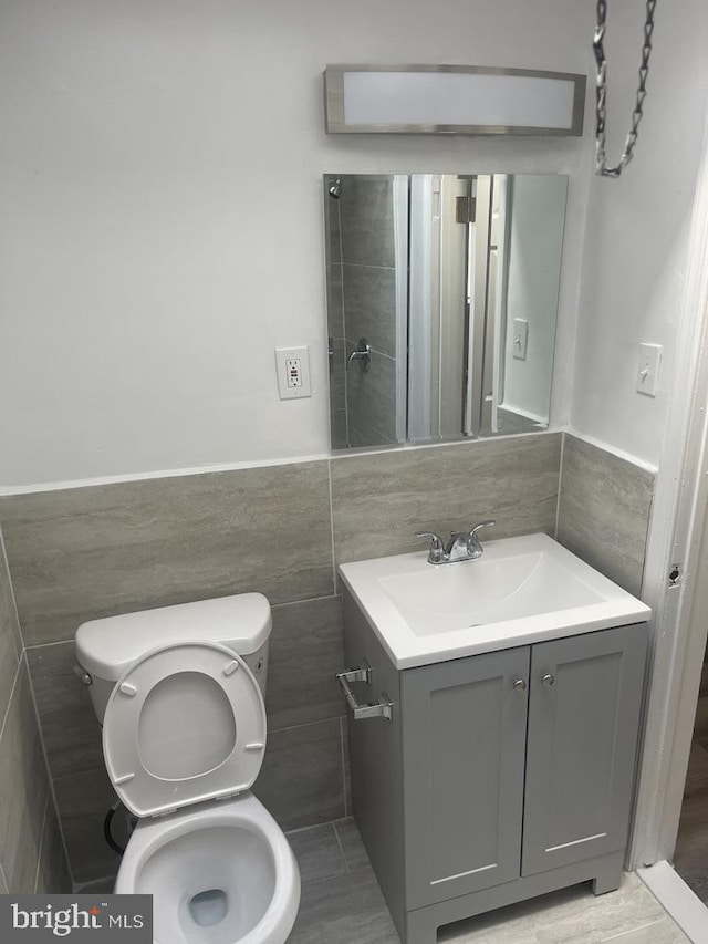 bathroom featuring tile walls, vanity, and toilet