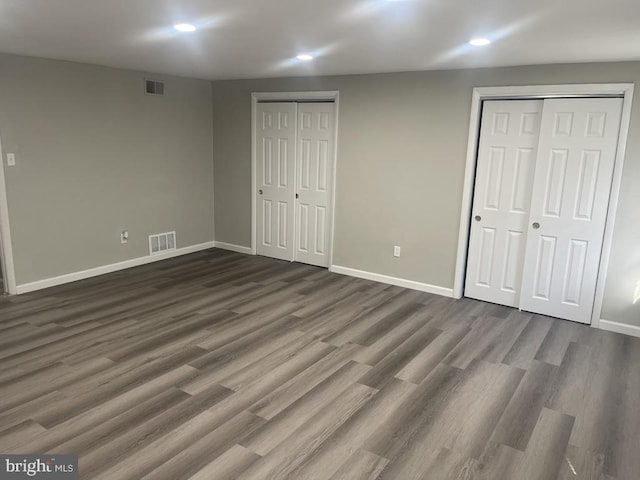 unfurnished bedroom featuring multiple closets and dark wood-type flooring