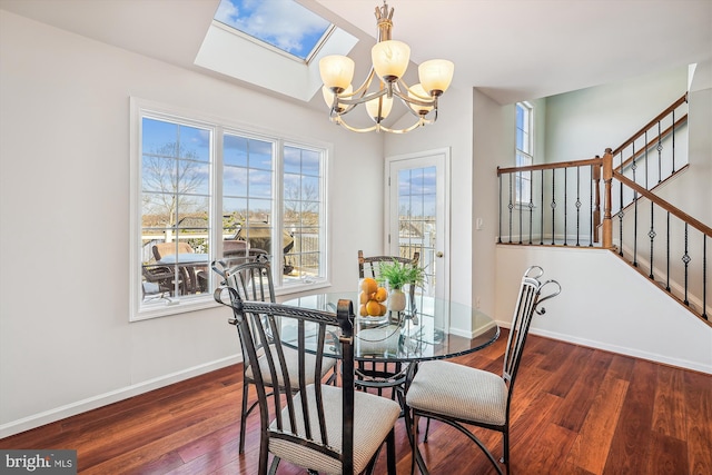 dining space with a skylight, dark hardwood / wood-style flooring, and an inviting chandelier