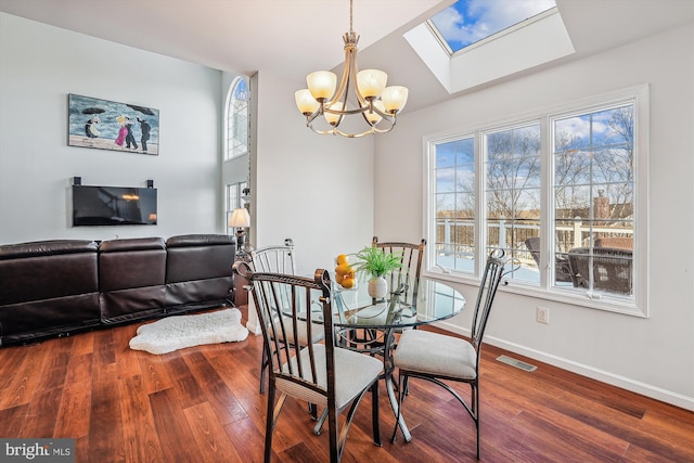 dining room featuring lofted ceiling with skylight, an inviting chandelier, and hardwood / wood-style flooring