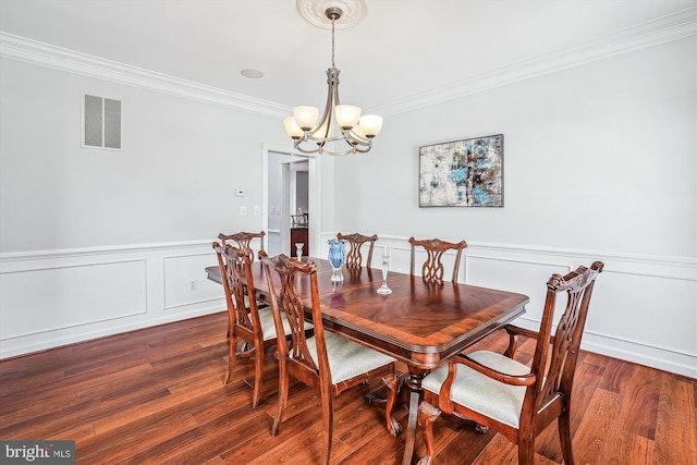 dining room featuring dark hardwood / wood-style flooring, ornamental molding, and a chandelier