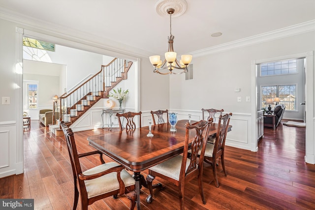 dining area with dark hardwood / wood-style flooring, crown molding, and a notable chandelier