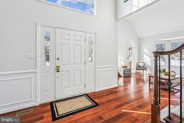 entryway with dark hardwood / wood-style floors and a towering ceiling