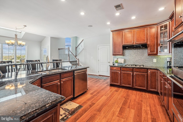 kitchen featuring sink, stainless steel appliances, dark stone counters, a chandelier, and hardwood / wood-style flooring