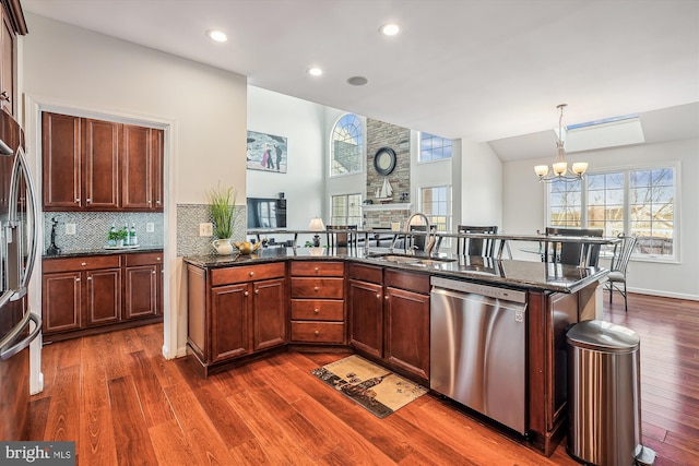 kitchen with stainless steel appliances, sink, a notable chandelier, dark stone countertops, and hanging light fixtures