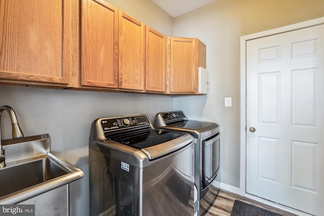 laundry area with cabinets, hardwood / wood-style floors, separate washer and dryer, and sink