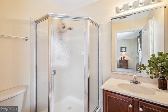 bathroom featuring toilet, an enclosed shower, and vanity