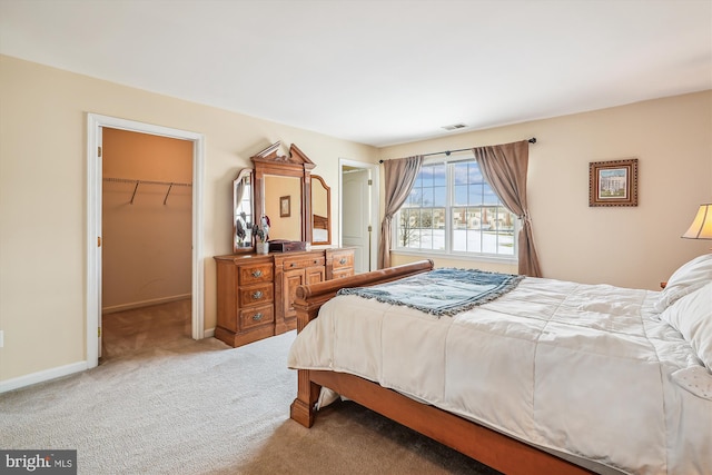 carpeted bedroom featuring a walk in closet and a closet