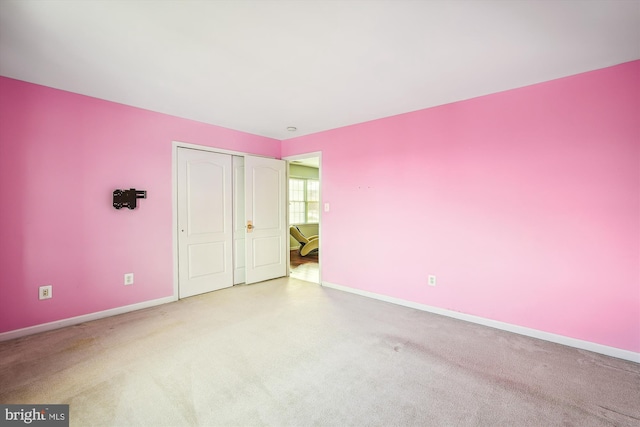 unfurnished bedroom with light colored carpet and a closet