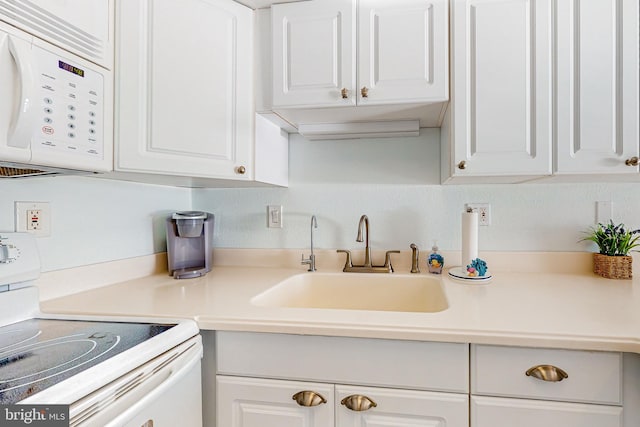 kitchen featuring white cabinetry, sink, and white appliances