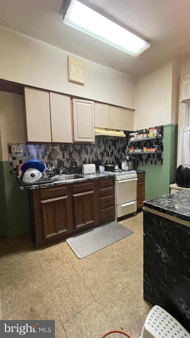 kitchen featuring sink, backsplash, and white range with gas cooktop