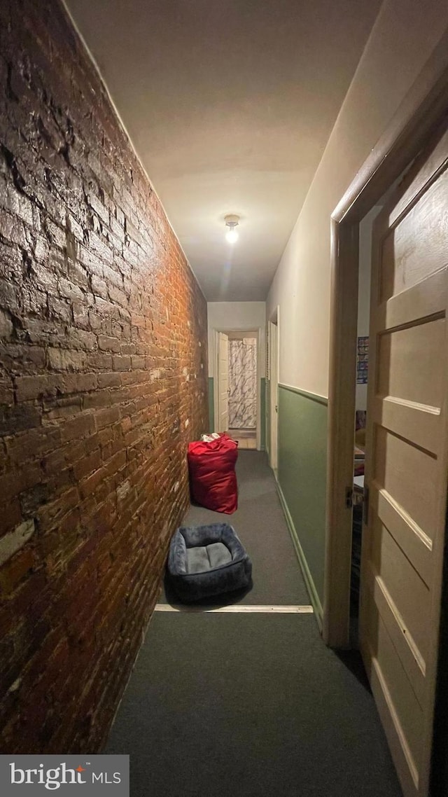 corridor with brick wall and carpet flooring