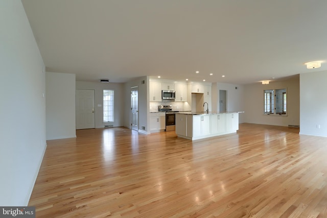 unfurnished living room featuring sink and light wood-type flooring