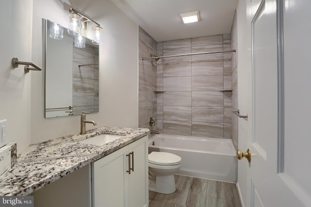 full bathroom featuring tiled shower / bath, vanity, hardwood / wood-style floors, and toilet