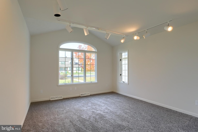 carpeted empty room featuring track lighting and vaulted ceiling