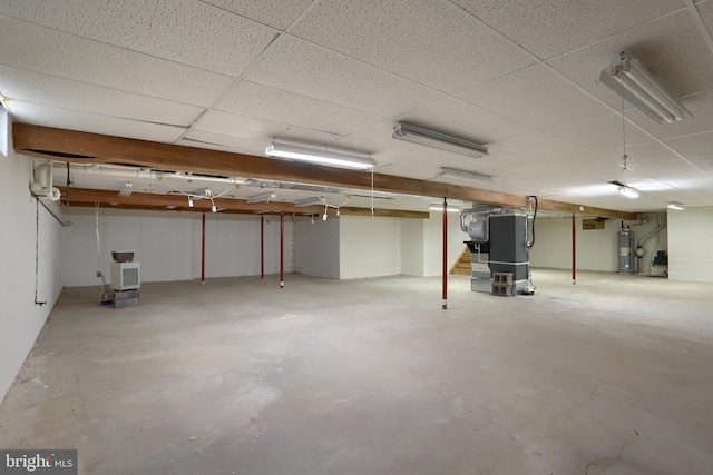 basement with a drop ceiling, electric water heater, and heating unit