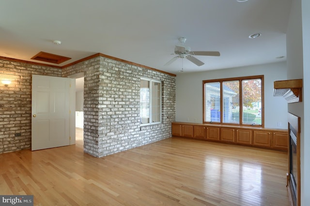 unfurnished living room featuring ceiling fan, brick wall, and light hardwood / wood-style flooring