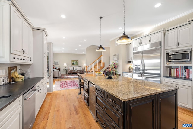 kitchen with a kitchen island, hanging light fixtures, light hardwood / wood-style floors, dark brown cabinetry, and built in appliances