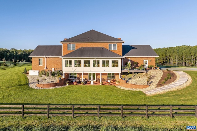 back of house with a patio area, a lawn, and a rural view