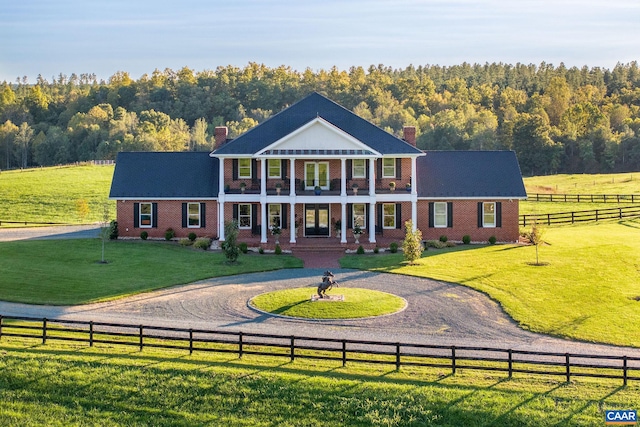 neoclassical / greek revival house with a front lawn and a rural view