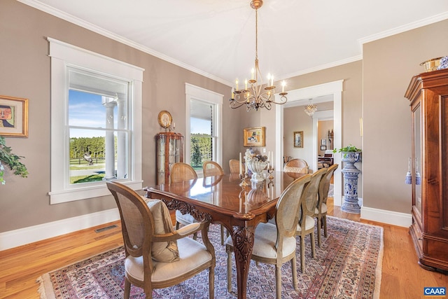 dining room with crown molding, a healthy amount of sunlight, a chandelier, and light wood-type flooring