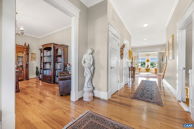 foyer featuring an inviting chandelier, light hardwood / wood-style flooring, and ornamental molding