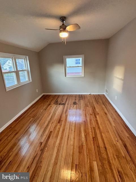 spare room featuring lofted ceiling, light wood-type flooring, and ceiling fan