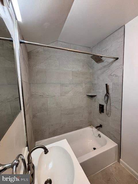 bathroom featuring tile patterned floors, vaulted ceiling, and tiled shower / bath combo