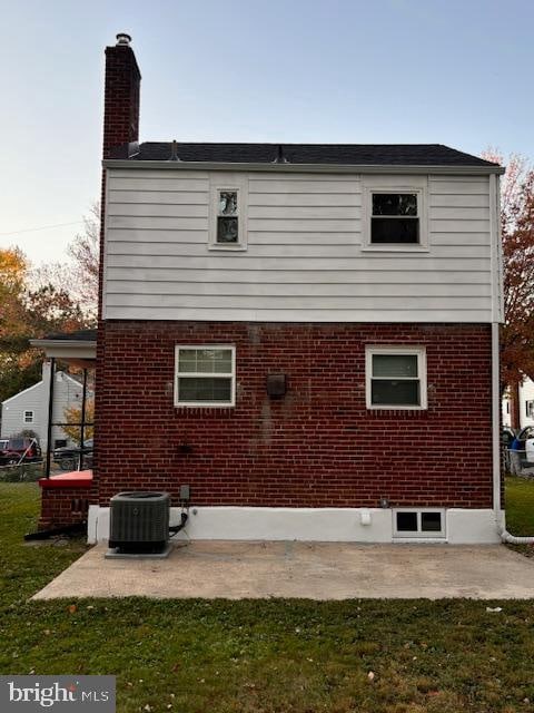 rear view of house with a lawn and central AC unit