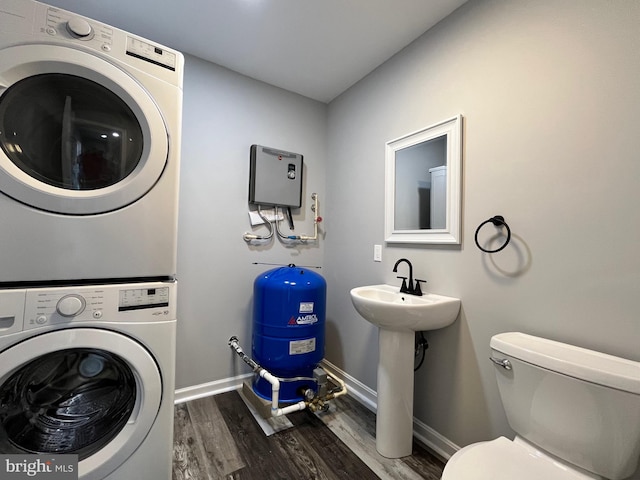 washroom with stacked washer / dryer and dark wood-type flooring