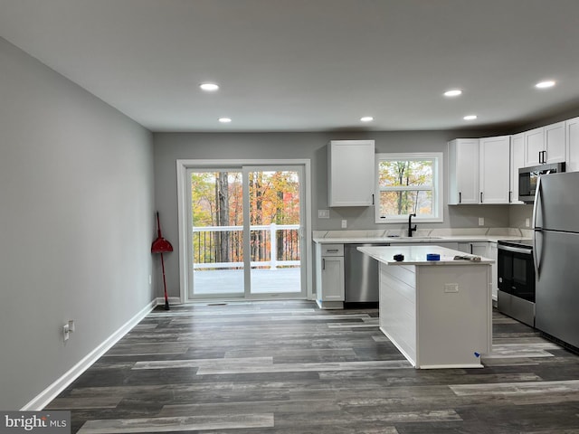 kitchen featuring white cabinetry, sink, a center island, dark wood-type flooring, and appliances with stainless steel finishes