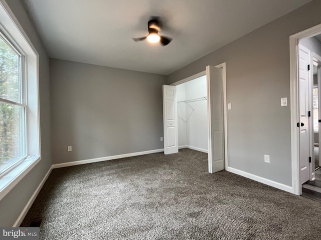 unfurnished bedroom featuring ceiling fan, a closet, and dark carpet