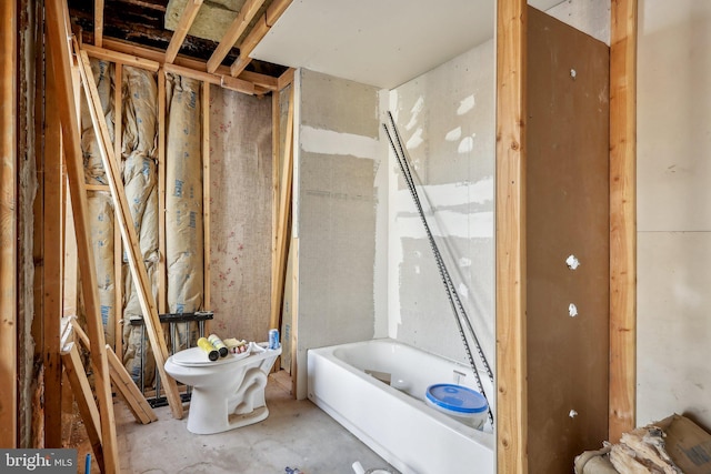 bathroom with a tub to relax in, toilet, and concrete floors