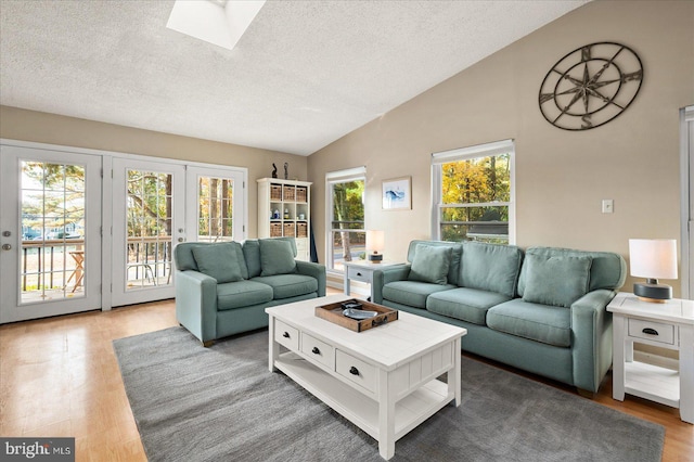 living room featuring a skylight, a textured ceiling, hardwood / wood-style flooring, and french doors