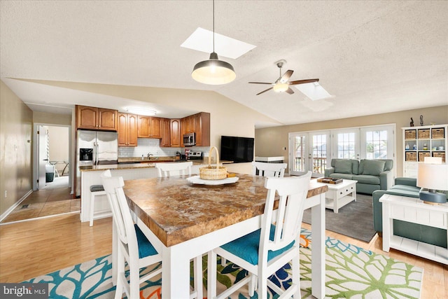 702 Ocean Pkwy, Ocean Pines, MD 21811 - kitchen with a skylight, light wood-type flooring, vaulted ceiling, brown cabinetry, and stainless steel appliances