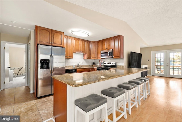 702 Ocean Pkwy, Ocean Pines, MD 21811 - kitchen with stainless steel appliances, a sink, brown cabinetry, a peninsula, and lofted ceiling