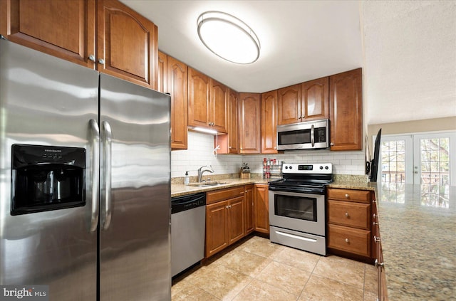 kitchen featuring light tile patterned flooring, sink, appliances with stainless steel finishes, light stone countertops, and backsplash