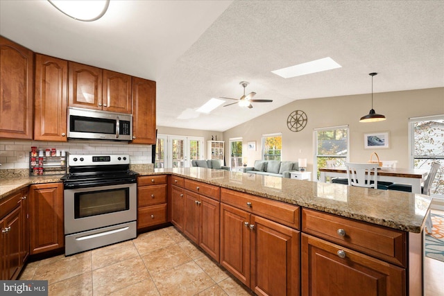 702 Ocean Pkwy, Ocean Pines, MD 21811 - kitchen featuring appliances with stainless steel finishes, a skylight, vaulted ceiling, brown cabinetry, and decorative backsplash