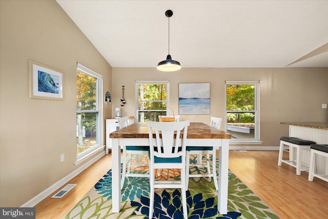 dining area with light wood-type flooring and lofted ceiling