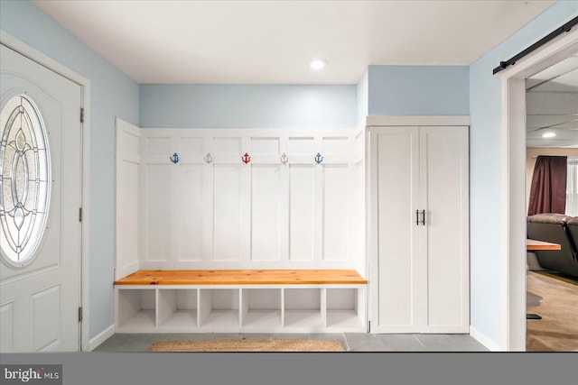 mudroom with a barn door and tile patterned flooring