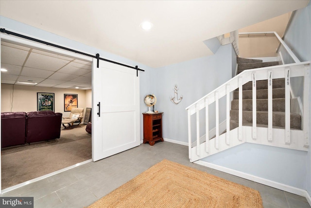 foyer entrance with a paneled ceiling, a barn door, and carpet flooring