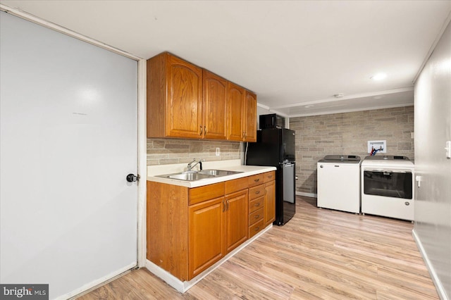 kitchen featuring washer and clothes dryer, black refrigerator, sink, and light hardwood / wood-style floors