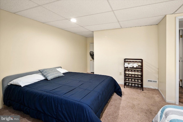 bedroom with a paneled ceiling and light carpet